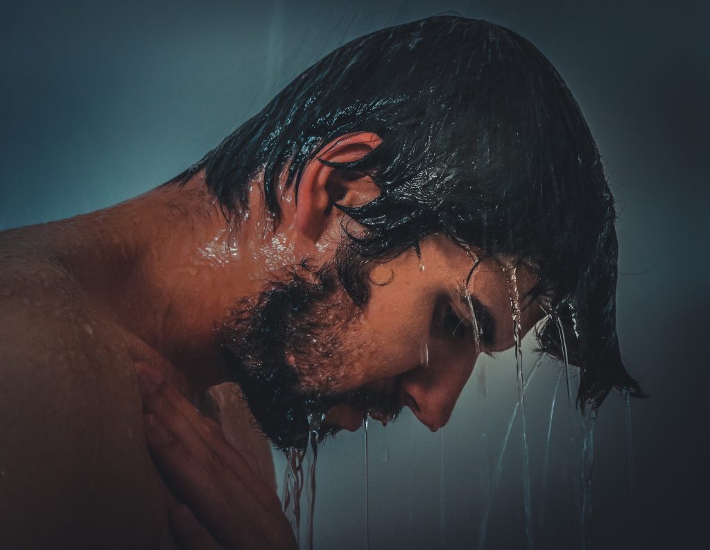Ein Mann hält seinen Kopf unter die Dusche. Quelle Pixabay: https://pixabay.com/photos/man-male-model-person-young-979980/