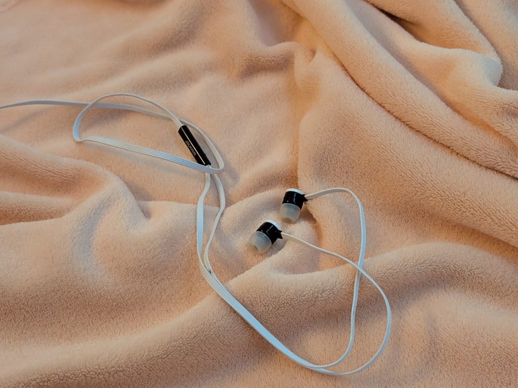 Podcast zum Einschlafen Kopfhörer auf einer orangen Kuscheldecke