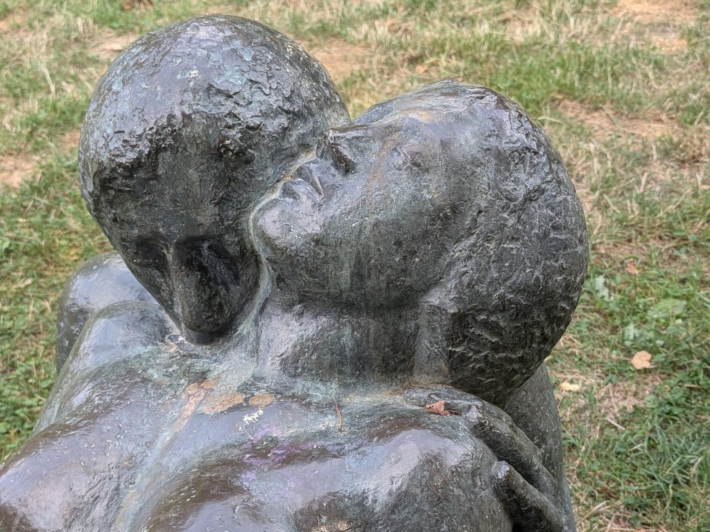 einschlafen-loslassen-geborgenheit Skulptur von einer Frau, die sich entspannt mit geschlossenen augen an die Schulter ihres Mannes legt