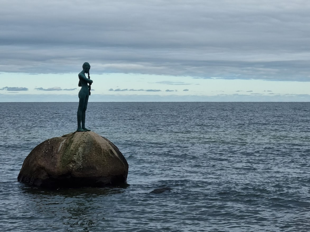 Ruhe Statue von einem Mädchen auf einem Stein im Meer